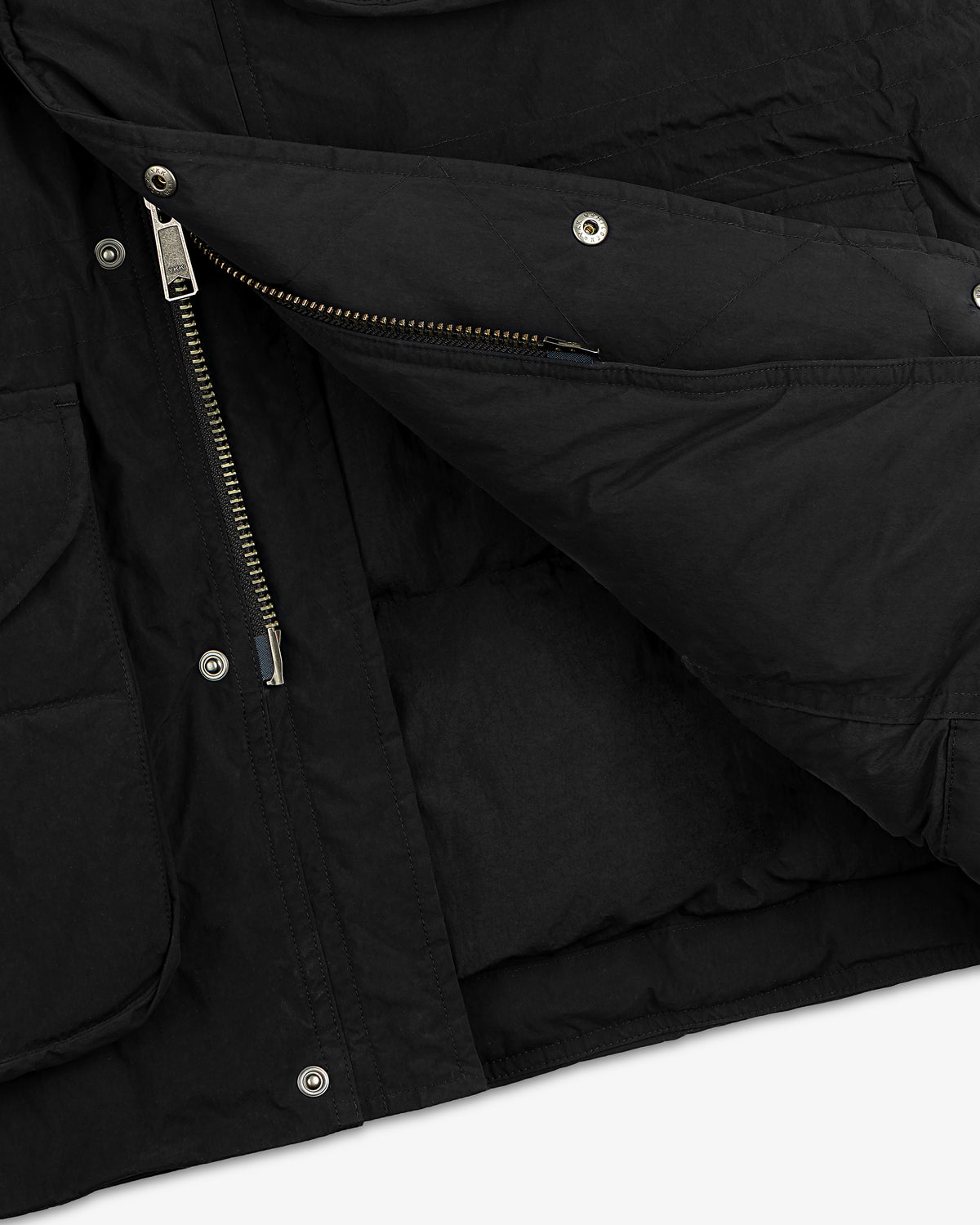 Close-up of a black quilted Down-Filled Surplus Parka with a metal zipper and snap button closures.