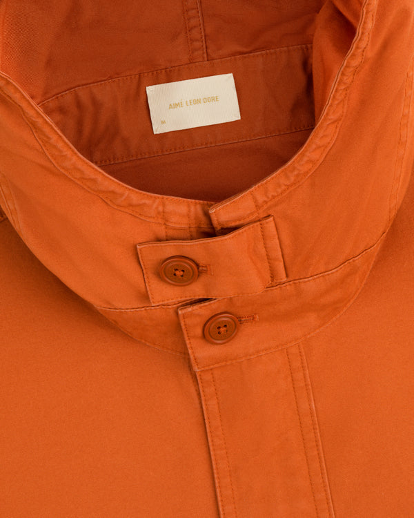Close-up of a Garment Washed Anorak collar in orange, featuring two buttons and a branded neck label.