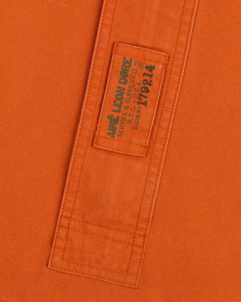 Orange Garment Washed Anorak fabric with a stitched rectangular patch featuring branded text and an issue number.