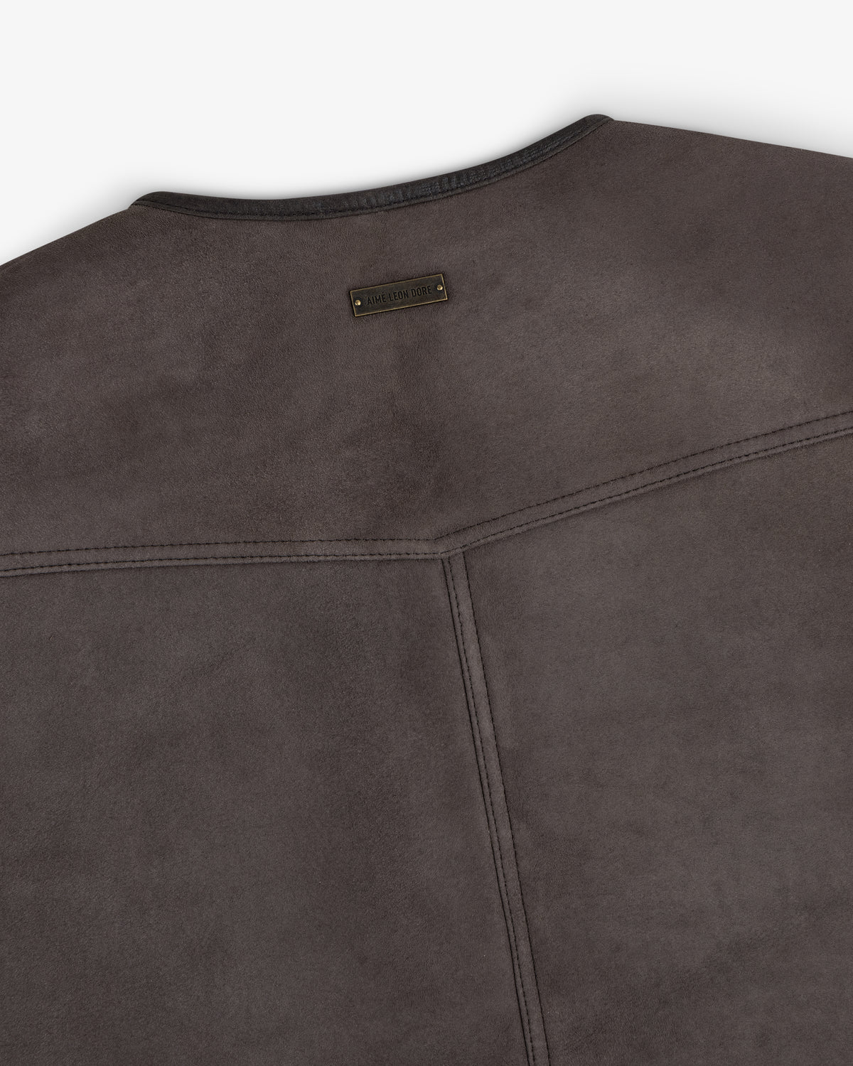 Back view of a charcoal grey Shearling Biker Vest featuring a small rectangular metal logo plate at the neckline.