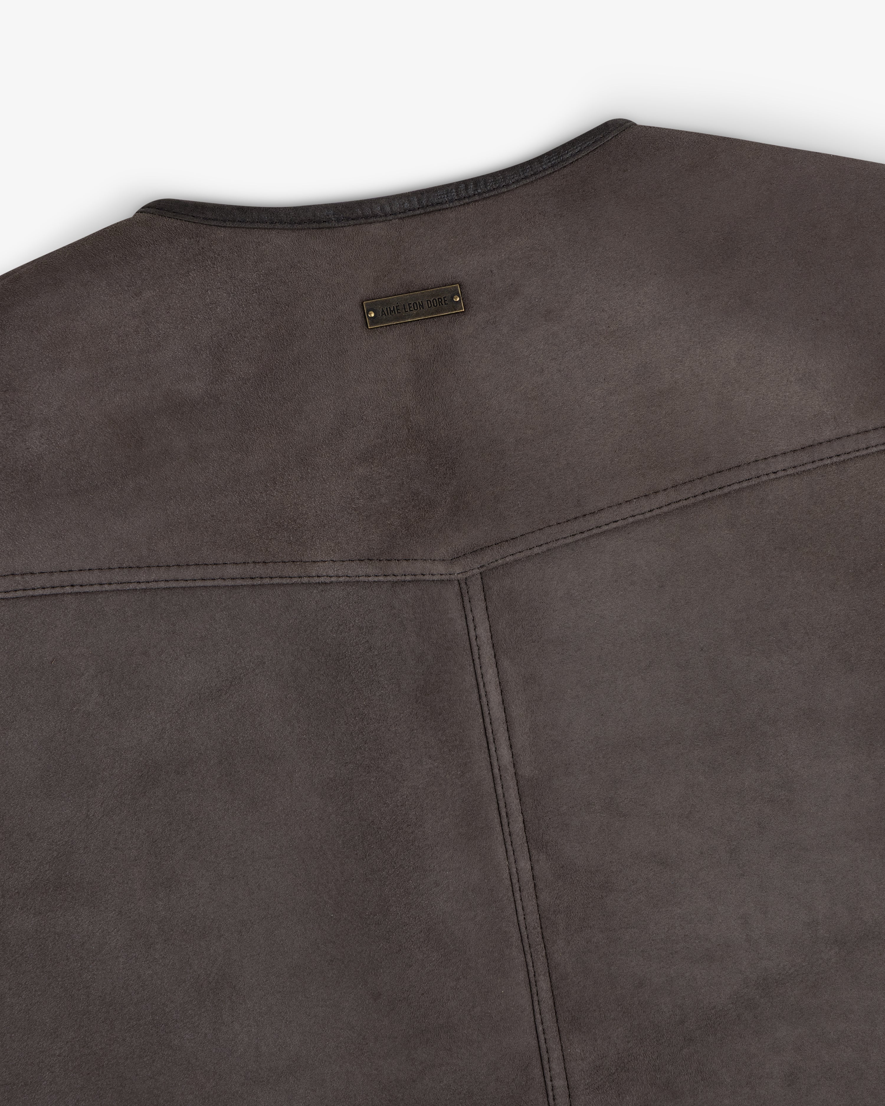 Back view of a charcoal grey Shearling Biker Vest featuring a small rectangular metal logo plate at the neckline.