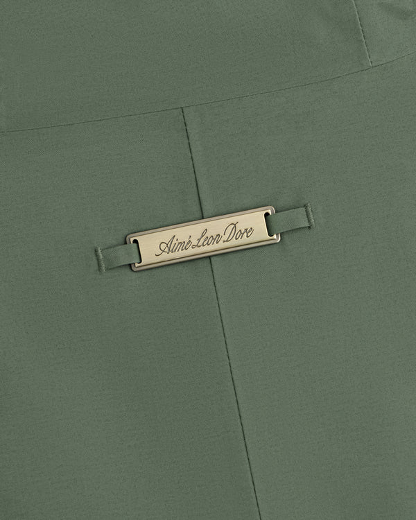 Olive green GORE-TEX Down Filled Fishtail Parka fabric with a rectangular metal plaque engraved Aimé Leon Dore.