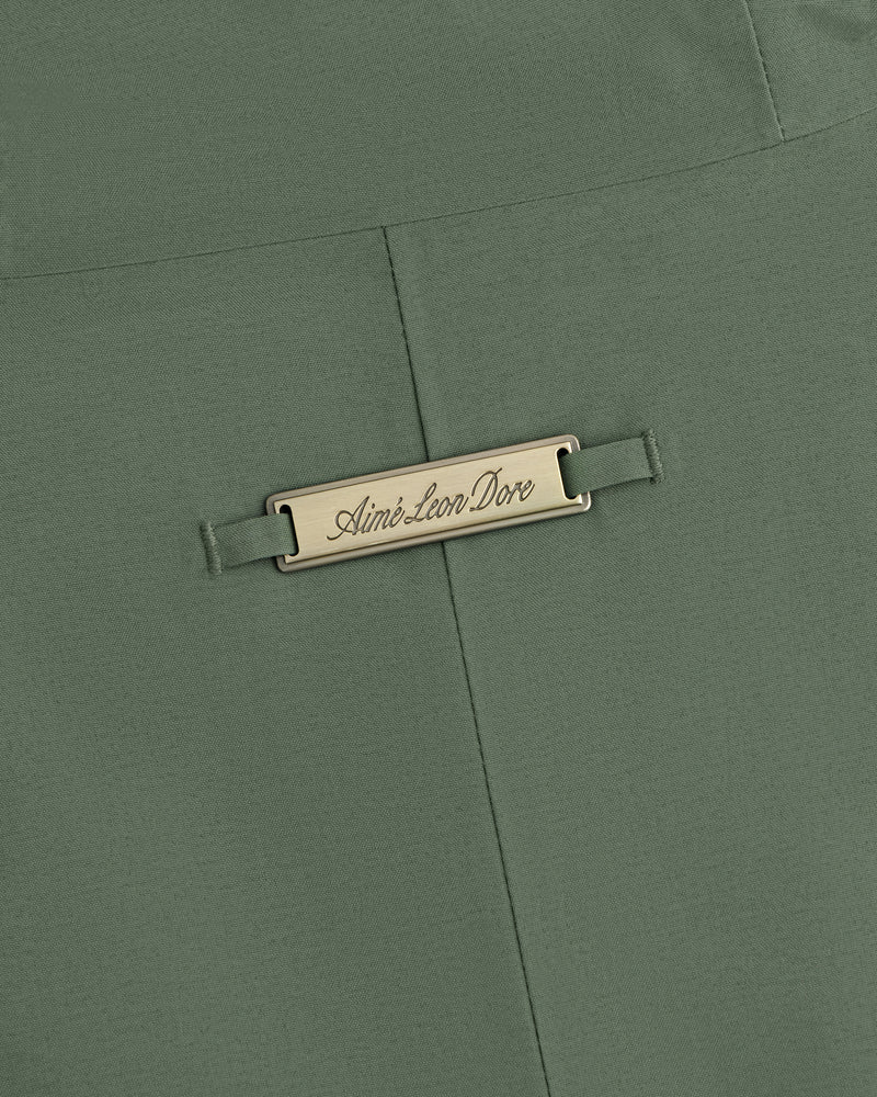 Olive green GORE-TEX Down Filled Fishtail Parka fabric with a rectangular metal plaque engraved Aimé Leon Dore.