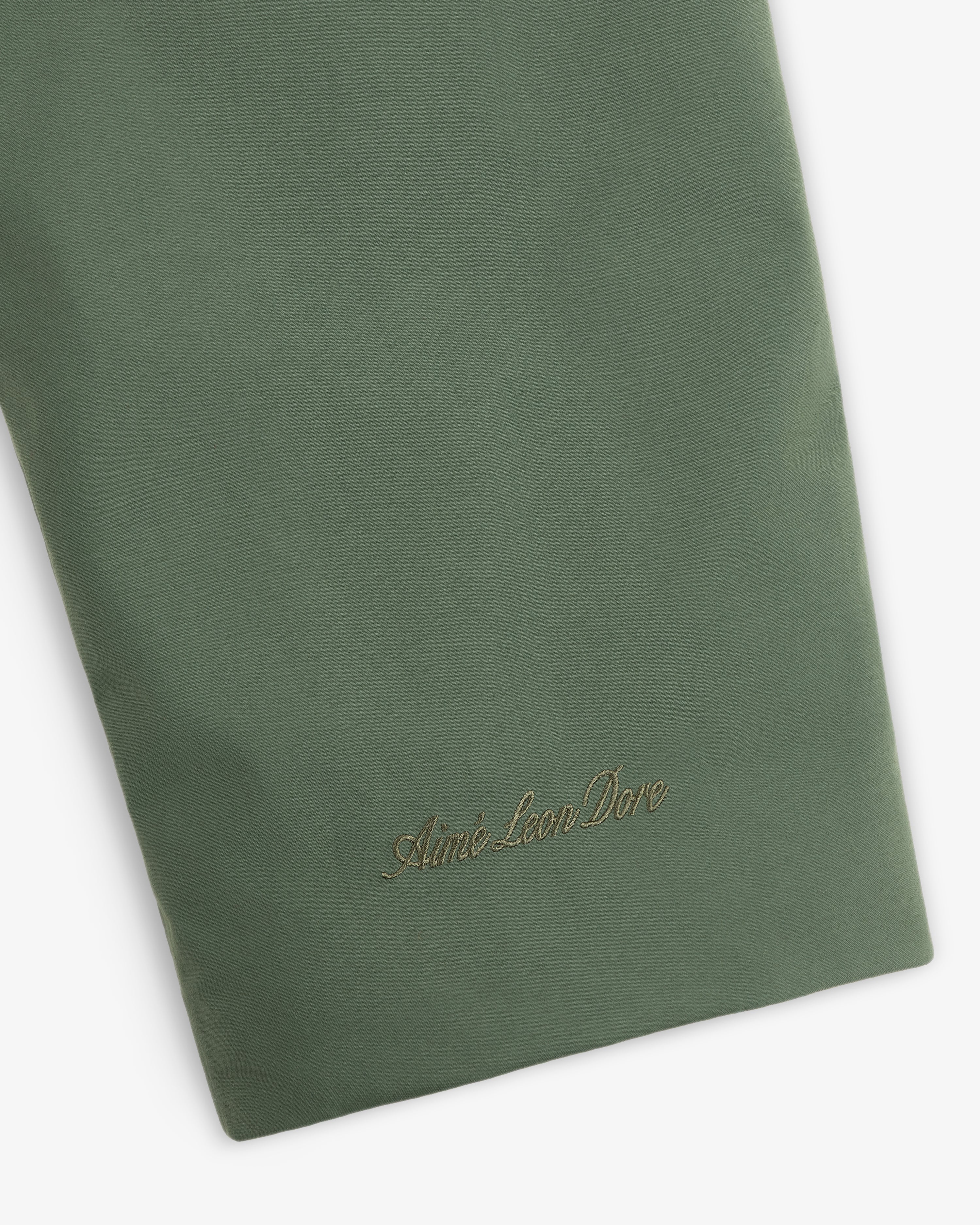 Olive green sleeve of the GORE-TEX Down Filled Fishtail Parka with an embroidered logo in script font near the cuff.