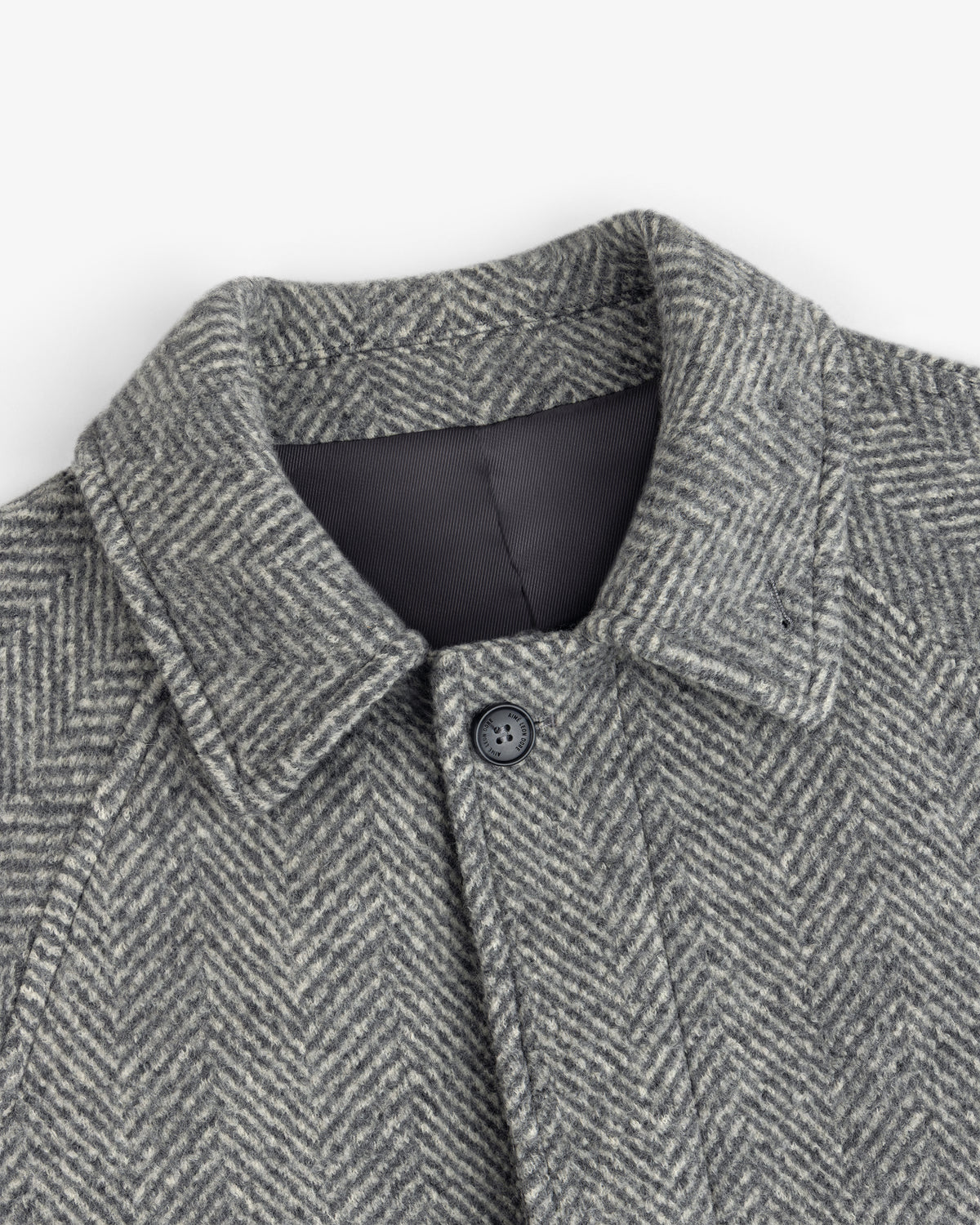 Wool Herringbone Overcoat in grey with a herringbone pattern, a collar, and a single button at the neck.