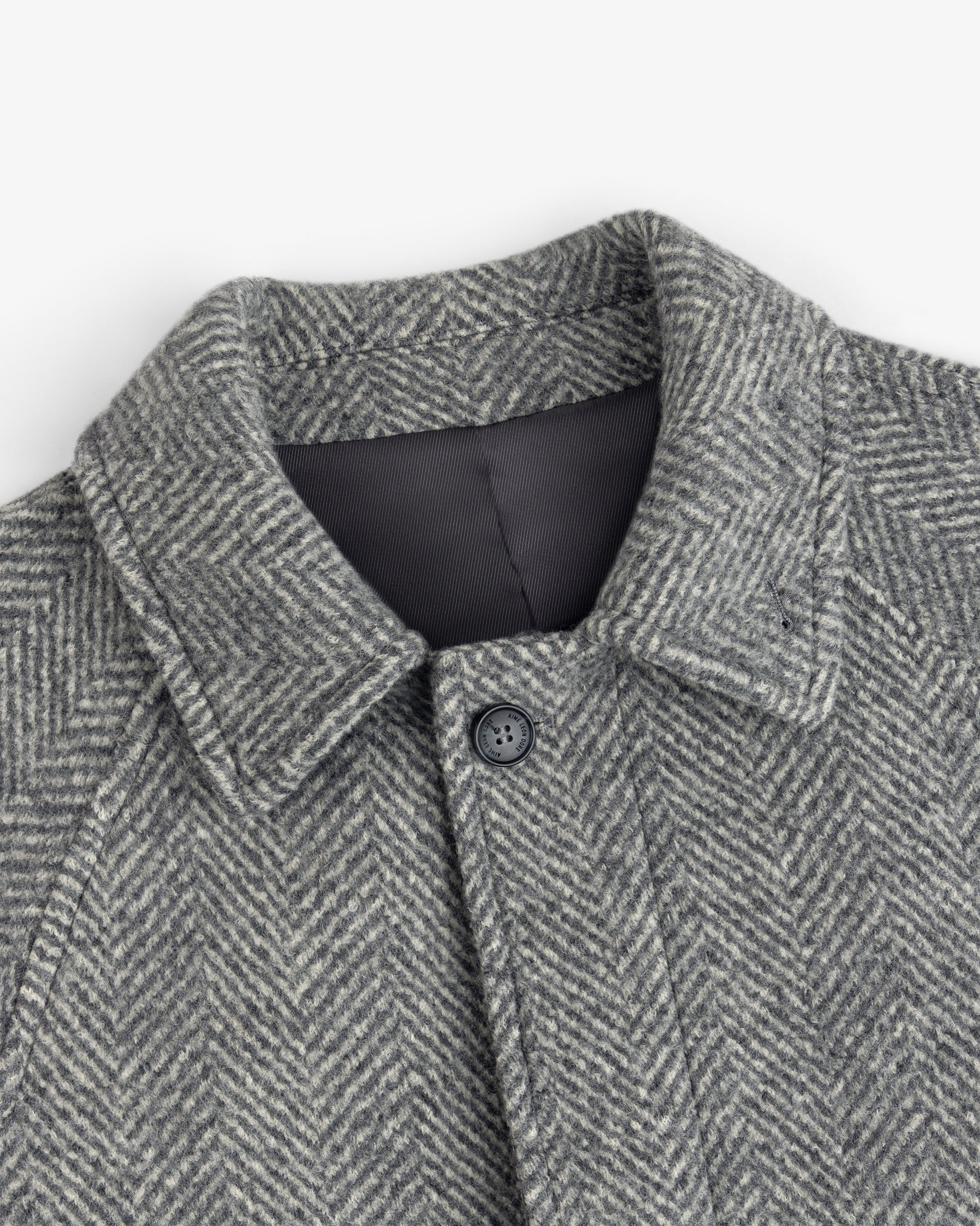 Wool Herringbone Overcoat in grey with a herringbone pattern, a collar, and a single button at the neck.