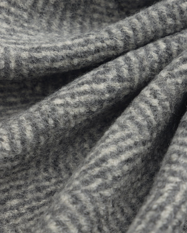 Close-up of the grey and white herringbone wool fabric of a Wool Herringbone Overcoat.