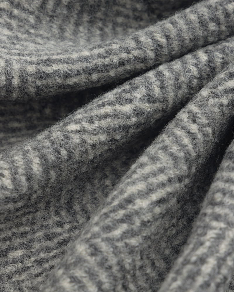 Close-up of the grey and white herringbone wool fabric of a Wool Herringbone Overcoat.