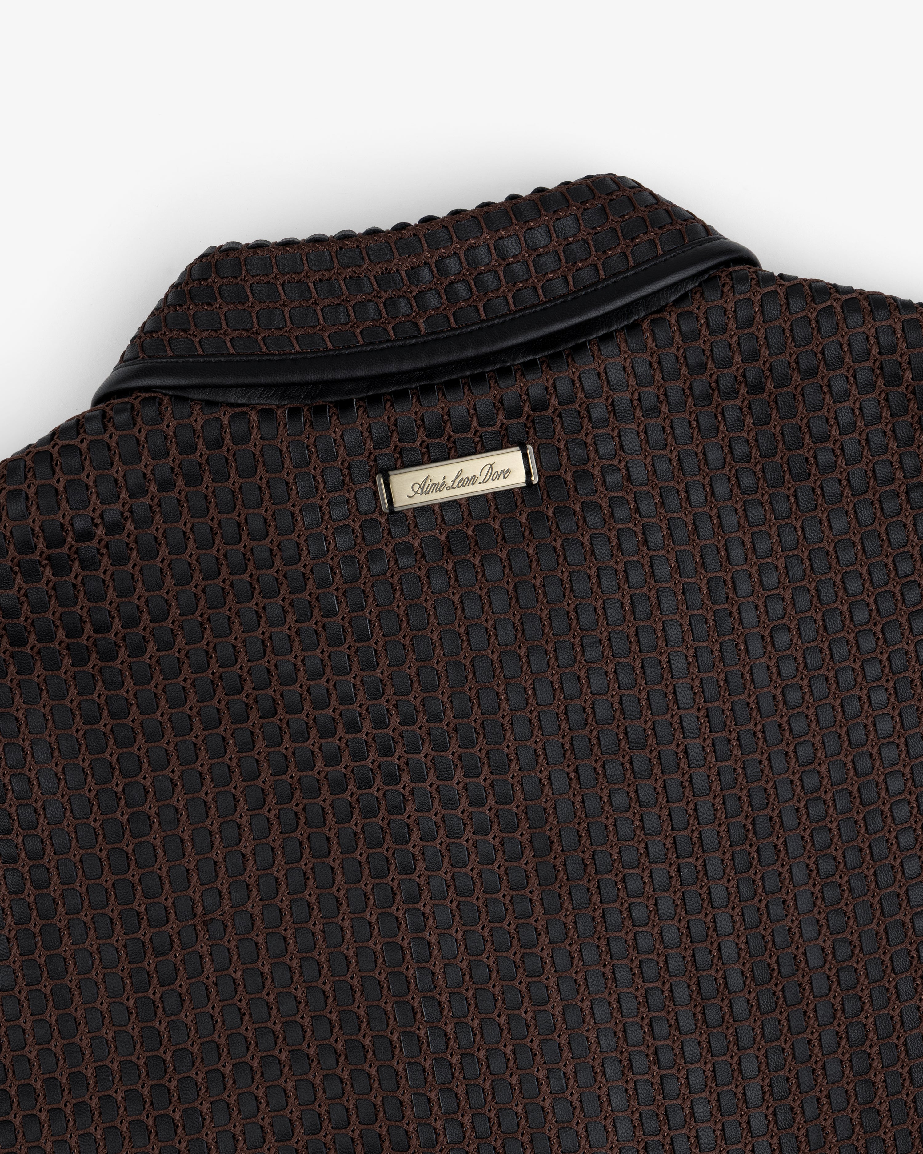 Close-up of a brown and black Woven Leather Jacket collar with a metal brand tag at the neckline.