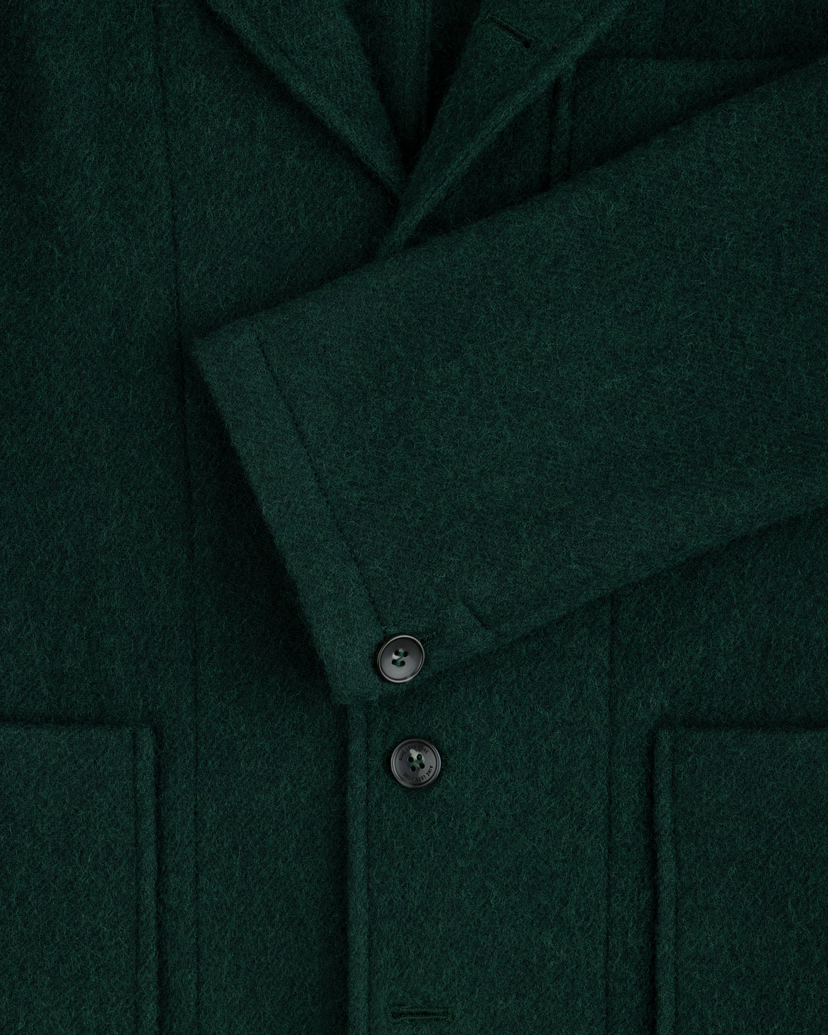 Close-up of a dark green Wool Sport Coat featuring a notched lapel, a buttoned sleeve cuff, and two patch pockets.