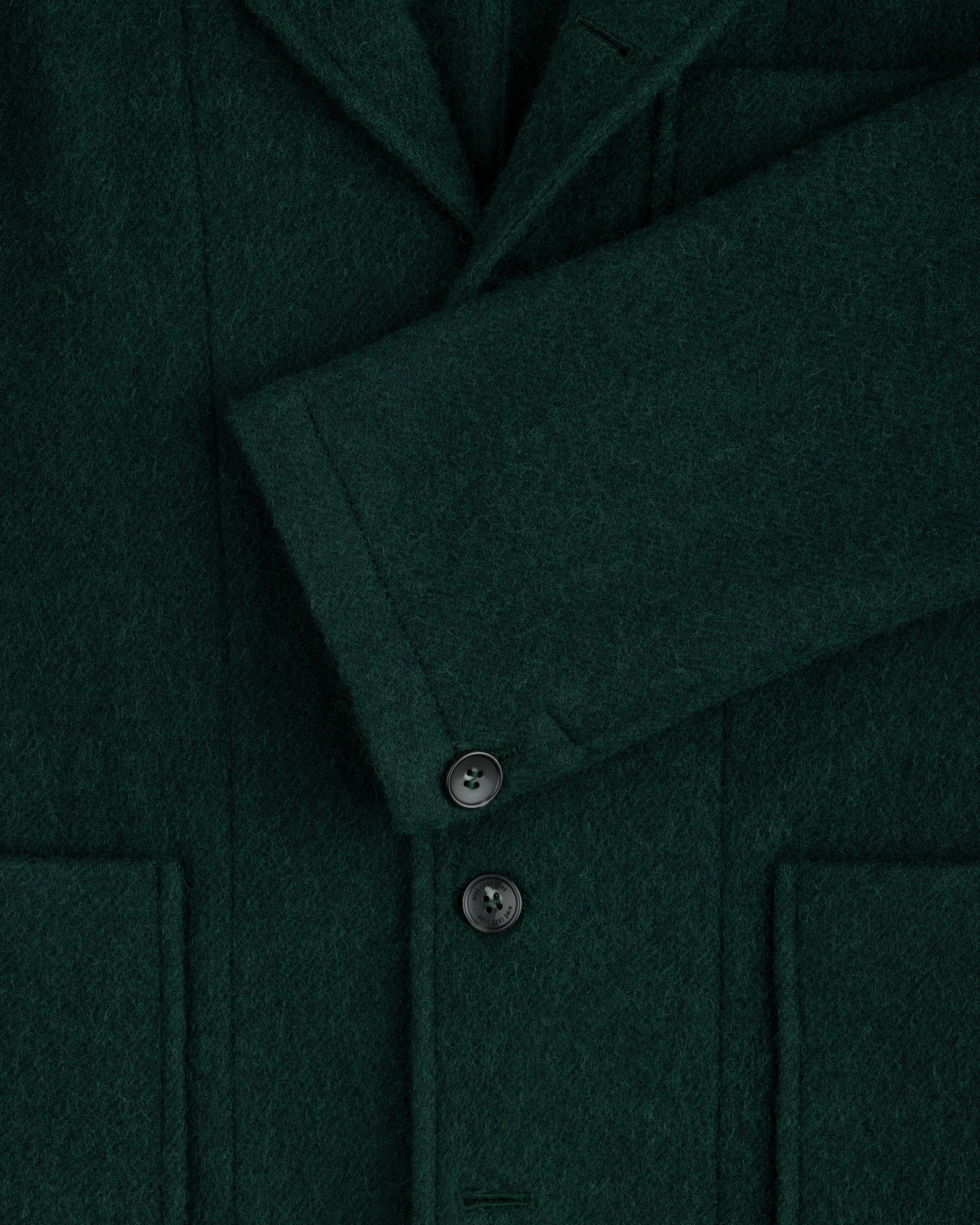 Close-up of a dark green Wool Sport Coat featuring a notched lapel, a buttoned sleeve cuff, and two patch pockets.