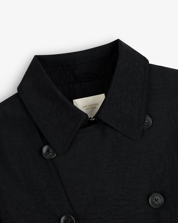 Close-up of a Double Breasted Nylon Trench Coat in black with textured fabric, collar, buttons, and inner label.