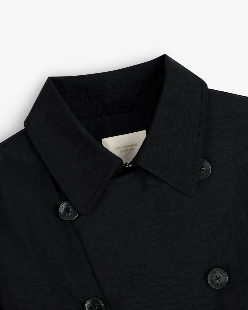 Close-up of a Double Breasted Nylon Trench Coat in black with textured fabric, collar, buttons, and inner label.