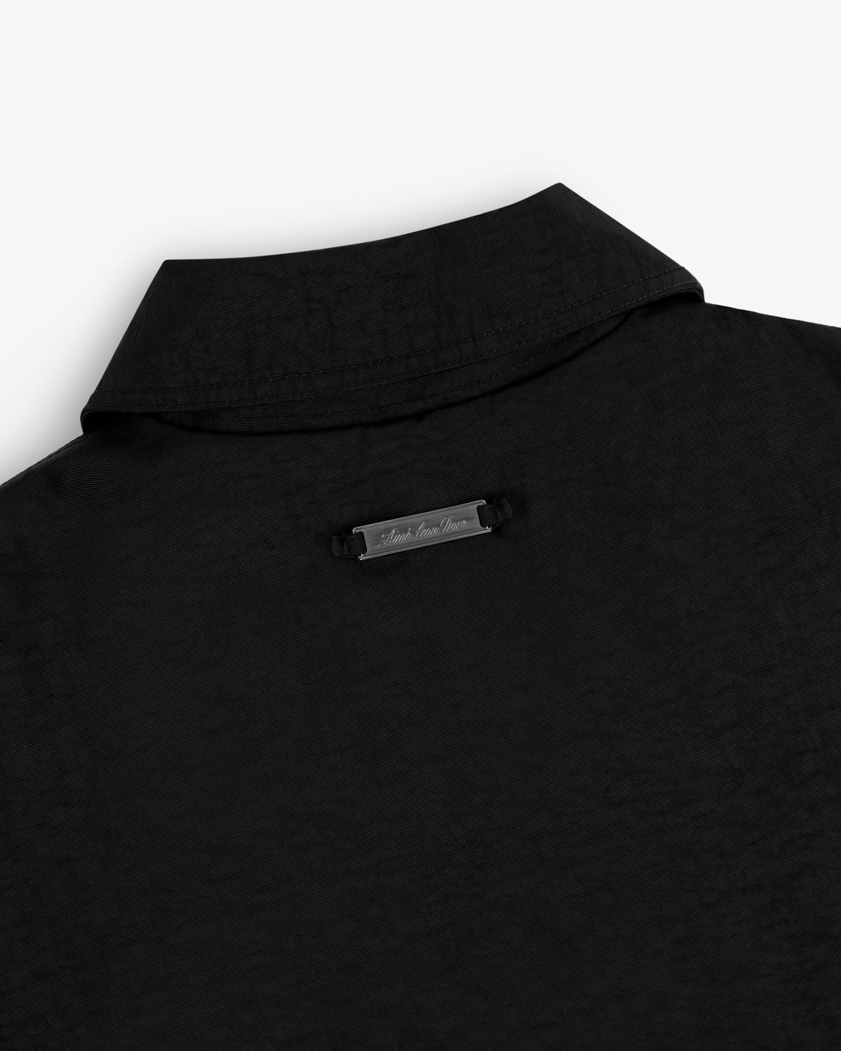 Close-up of the back collar of the Double Breasted Nylon Trench Coat with a small metallic nameplate below the collar.