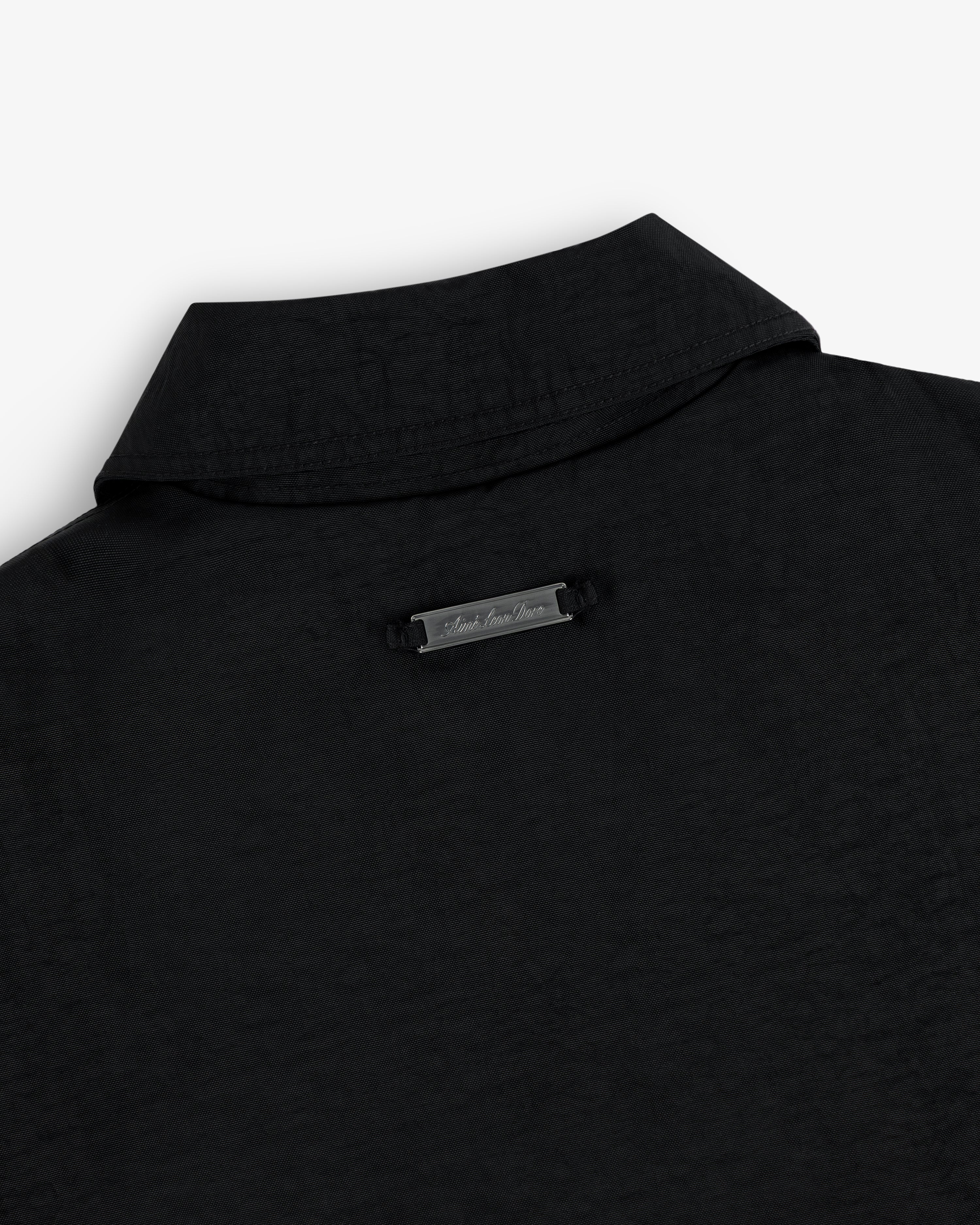 Close-up of the back collar of the Double Breasted Nylon Trench Coat with a small metallic nameplate below the collar.