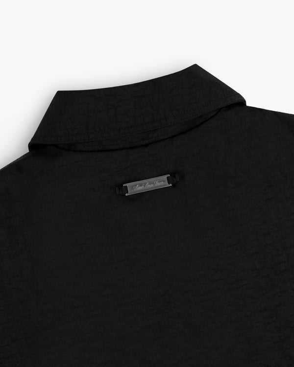 Close-up of the back collar of the Double Breasted Nylon Trench Coat with a small metallic nameplate below the collar.