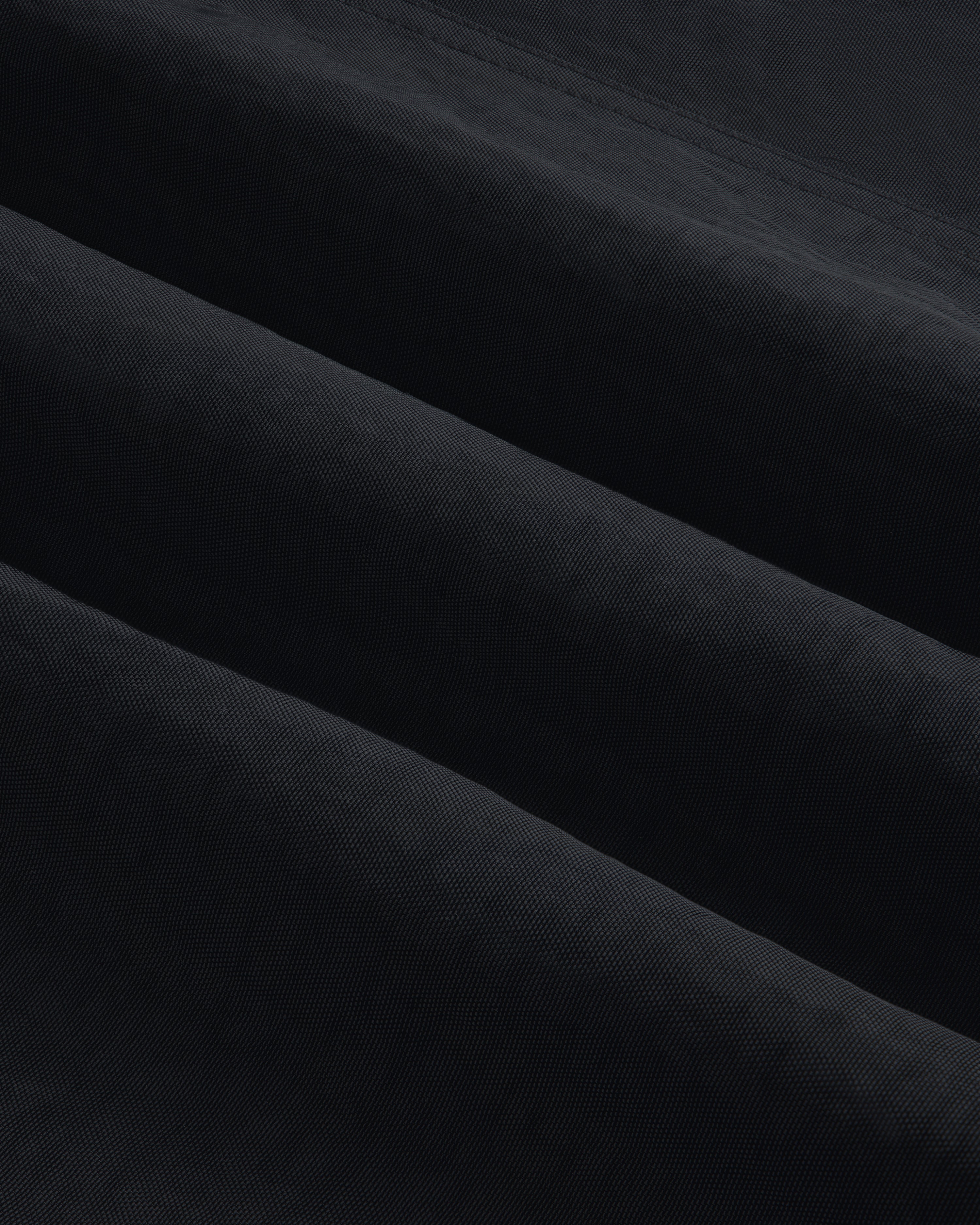Close-up of Double Breasted Nylon Trench Coat shows soft, folded fabric with subtle horizontal ridges and shadowed texture.