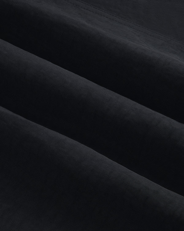 Close-up of Double Breasted Nylon Trench Coat shows soft, folded fabric with subtle horizontal ridges and shadowed texture.