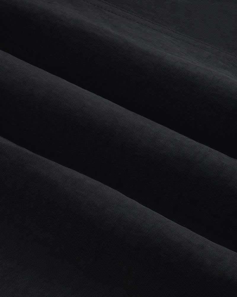 Close-up of Double Breasted Nylon Trench Coat shows soft, folded fabric with subtle horizontal ridges and shadowed texture.