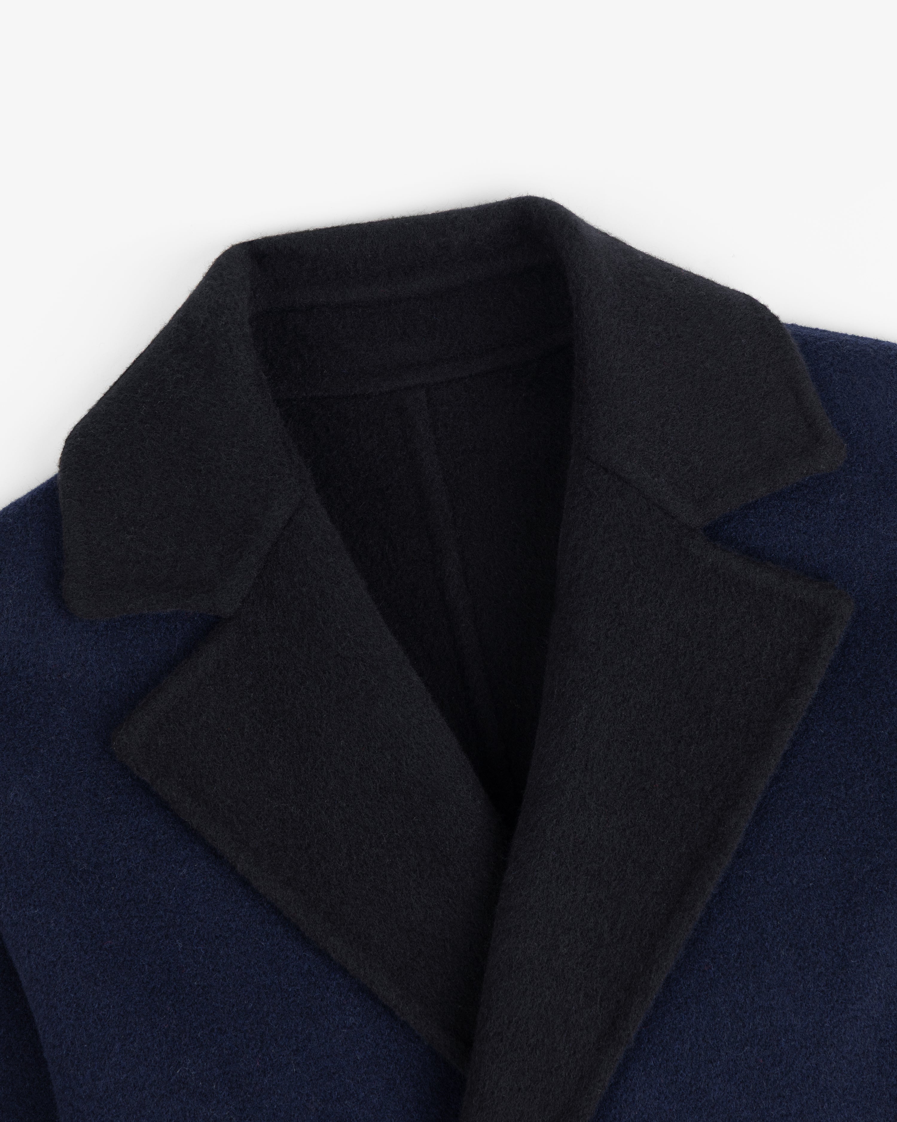 Close-up of a Reversible Double Breasted Top Coat with a dark navy body and a black collar and lapels.