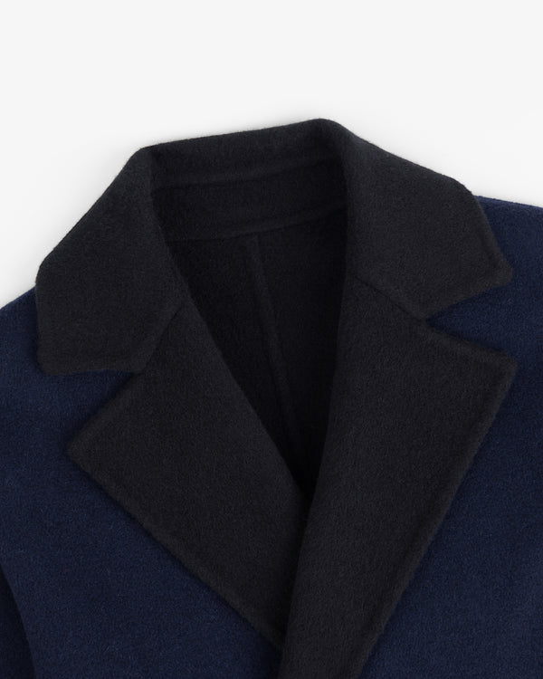 Close-up of a Reversible Double Breasted Top Coat with a dark navy body and a black collar and lapels.