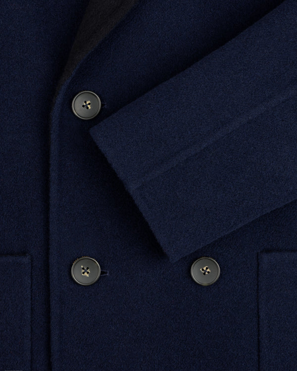Close-up of a navy blue Reversible Double Breasted Top Coat with dark buttons and a folded sleeve.