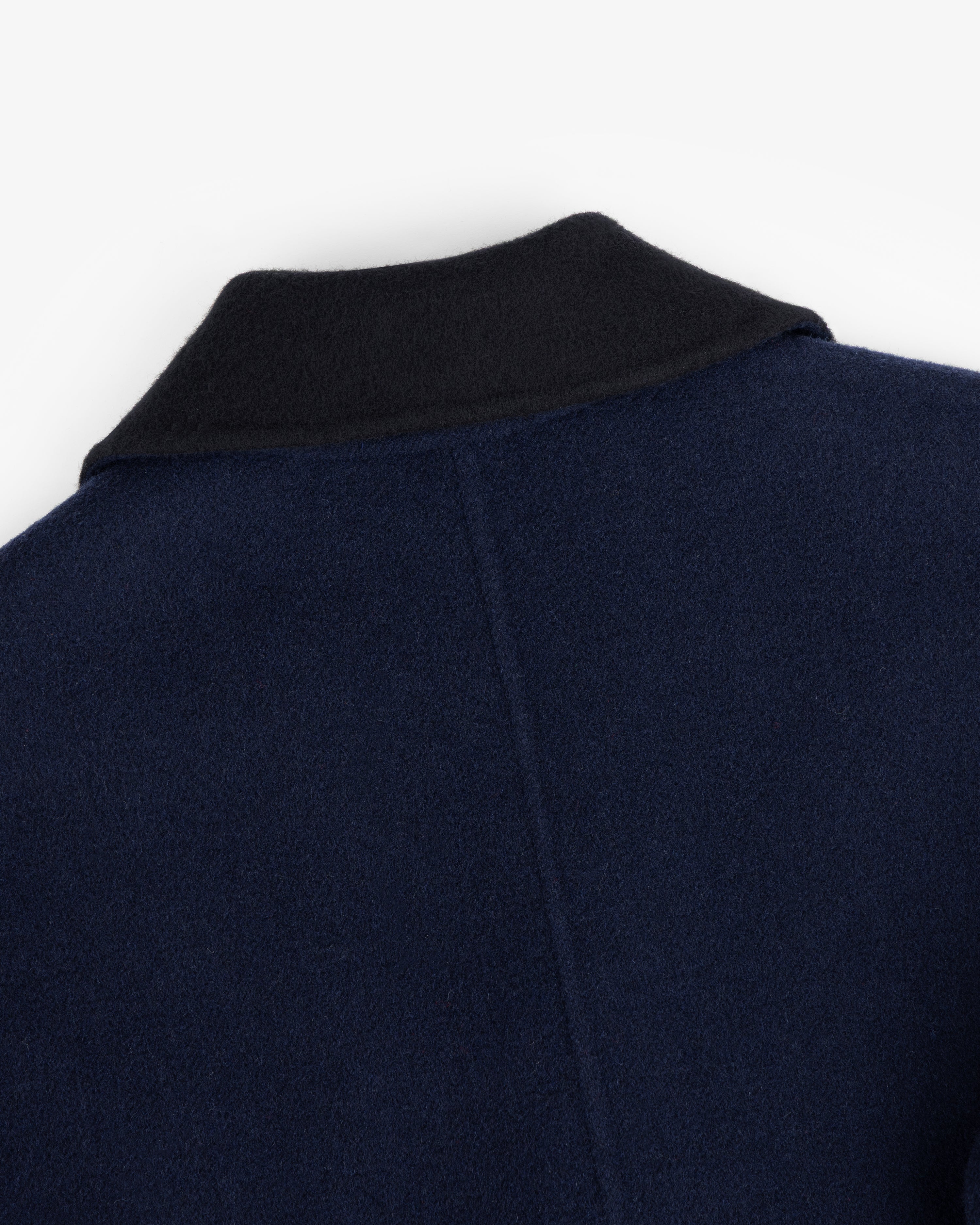 Close-up of a Reversible Double Breasted Top Coat in dark blue with a black collar.