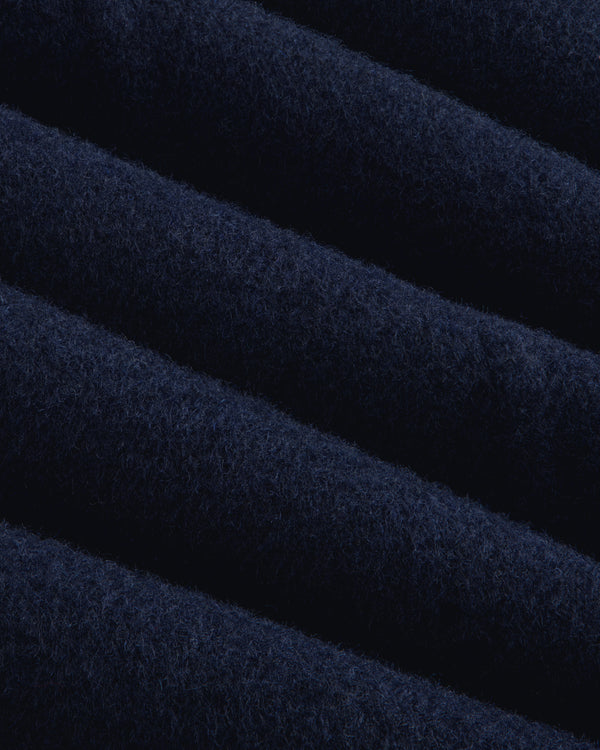Close-up of navy blue wool fabric on a Reversible Double Breasted Top Coat with diagonal folds.