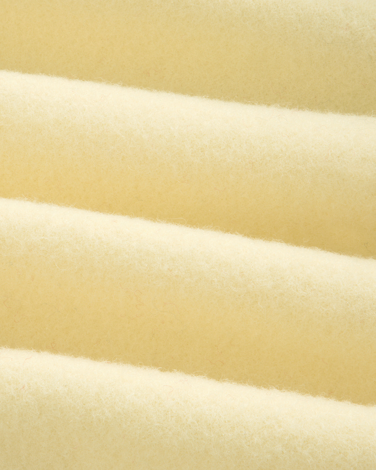 Close-up of a Wool Sportcoat in thick, cream-colored fabric with a soft, felted texture and diagonal folds.