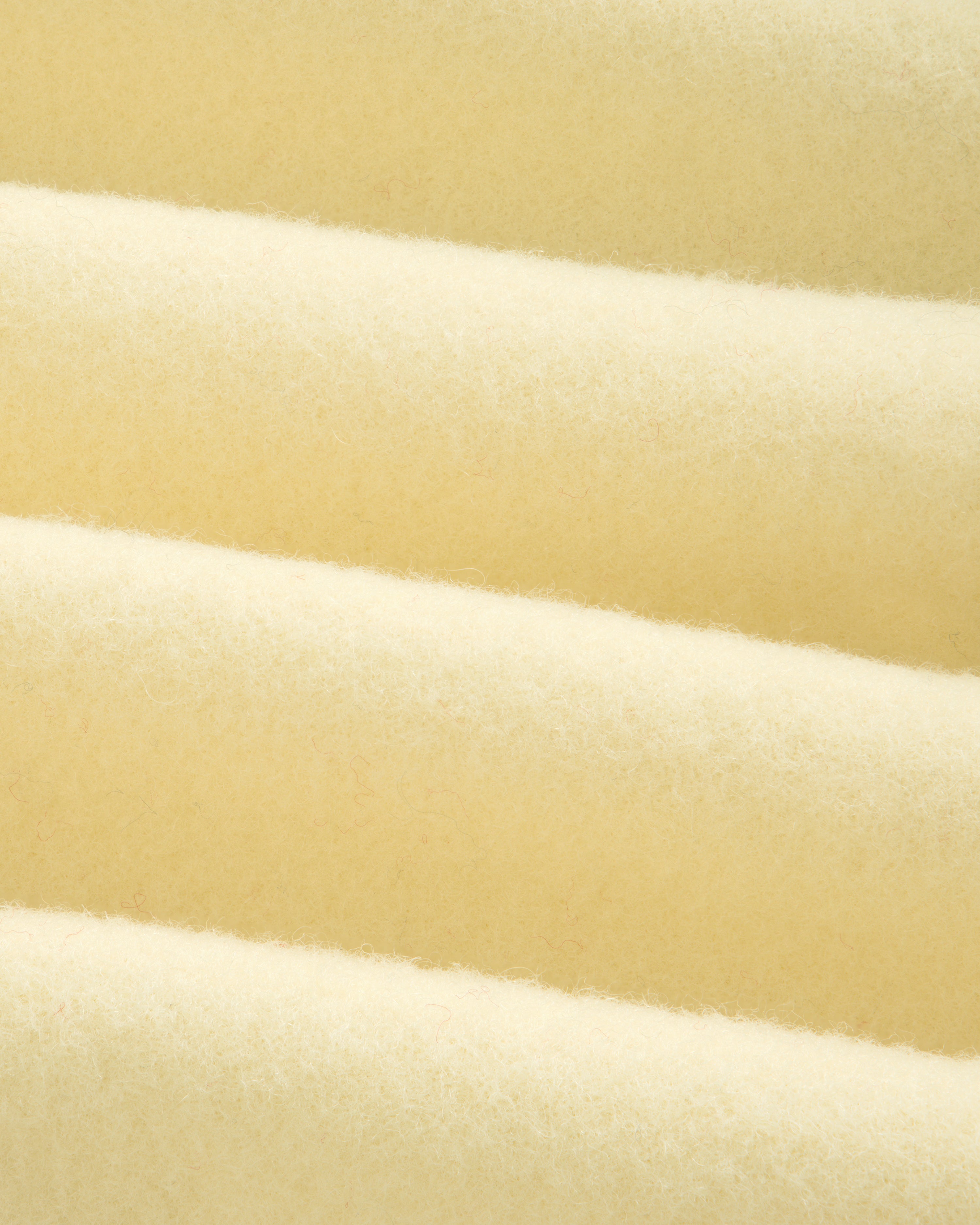 Close-up of a Wool Sportcoat in thick, cream-colored fabric with a soft, felted texture and diagonal folds.