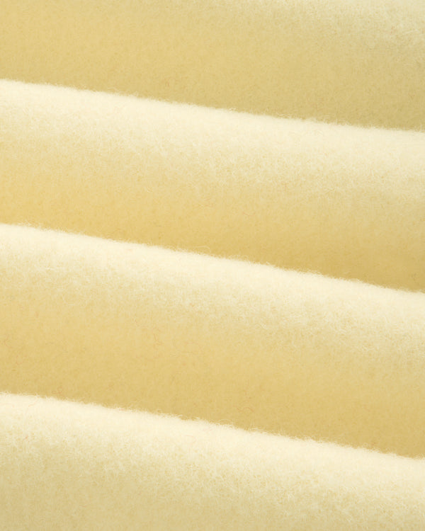 Close-up of a Wool Sportcoat in thick, cream-colored fabric with a soft, felted texture and diagonal folds.
