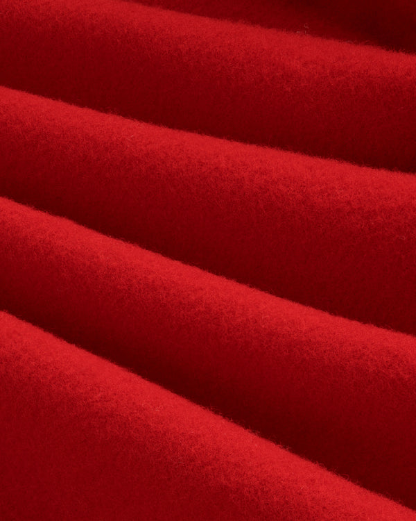 Close-up of thick, red felted Wool Sportcoat fabric folded into soft diagonal pleats.