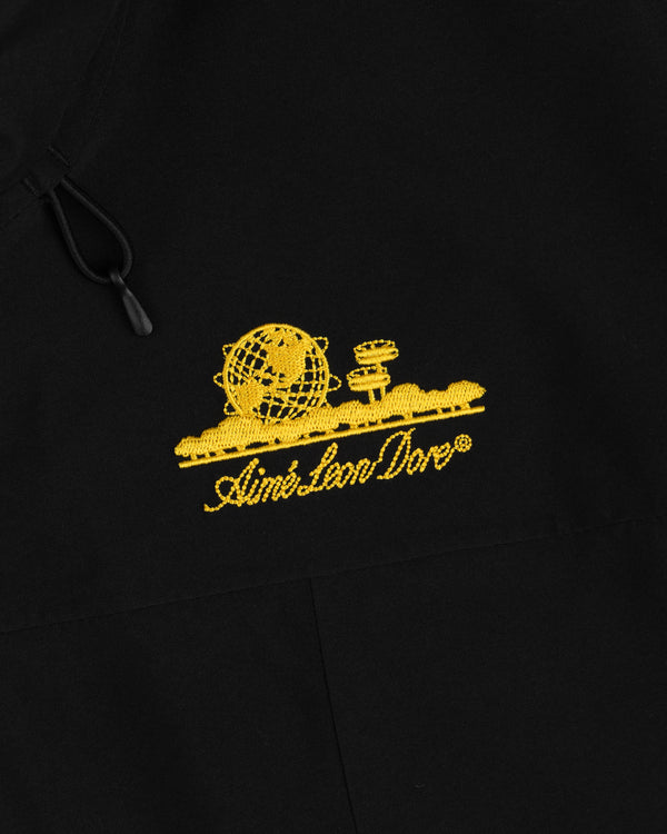 Cropped GORE-TEX Shell Jacket in black, featuring a yellow embroidered globe and tower logo above Aimé Leon Dore text.