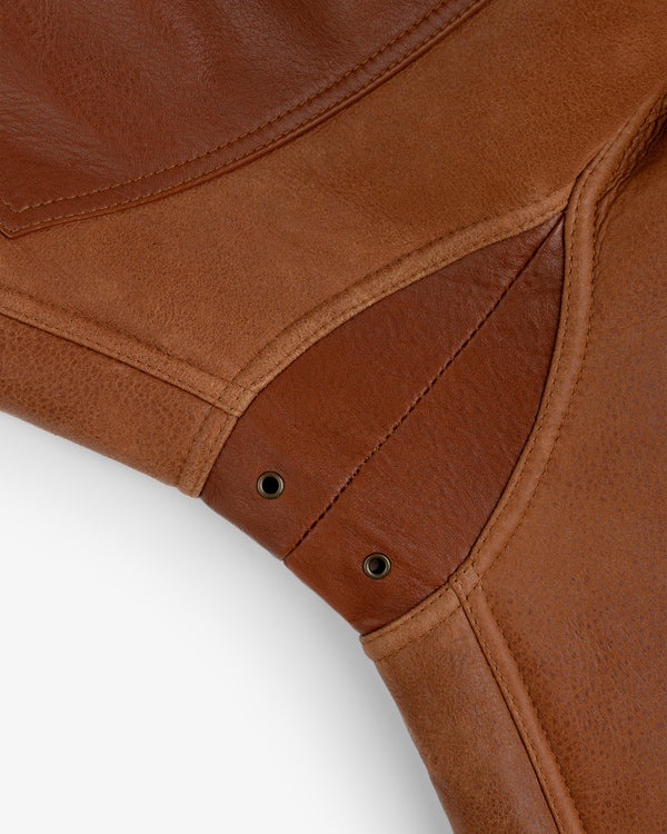Close-up of brown leather panels on a Shearling Bomber Jacket with reinforced stitching and metal eyelets.