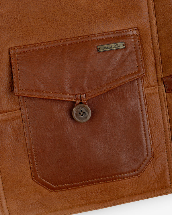 Brown leather pocket on a Shearling Bomber Jacket with a buttoned flap and a small rectangular metal logo tag.
