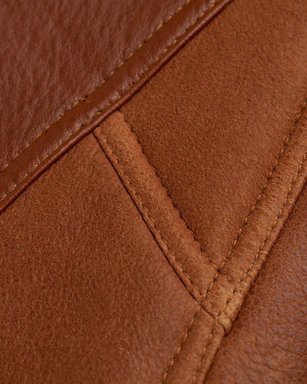 Close-up of brown leather and suede panels with stitched seams on a Shearling Bomber Jacket.