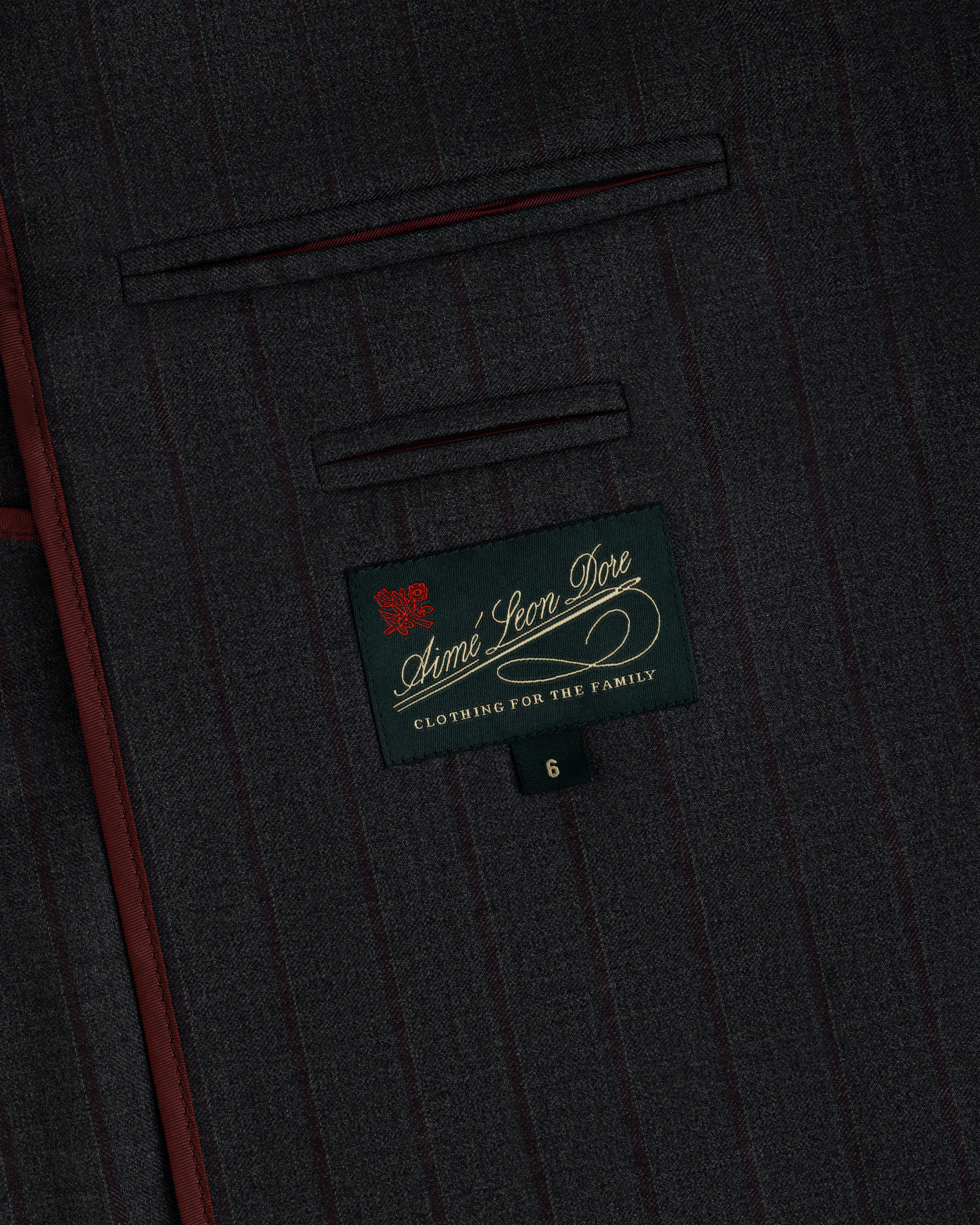 Collarless Striped Blazer in dark gray pinstriped fabric with a rectangular Aimé Leon Dore label and a size six tag.