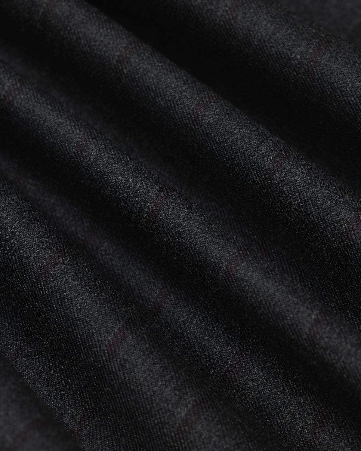 Close-up of a Collarless Striped Blazer in black fabric with faint, dark red pinstripes in soft folds.