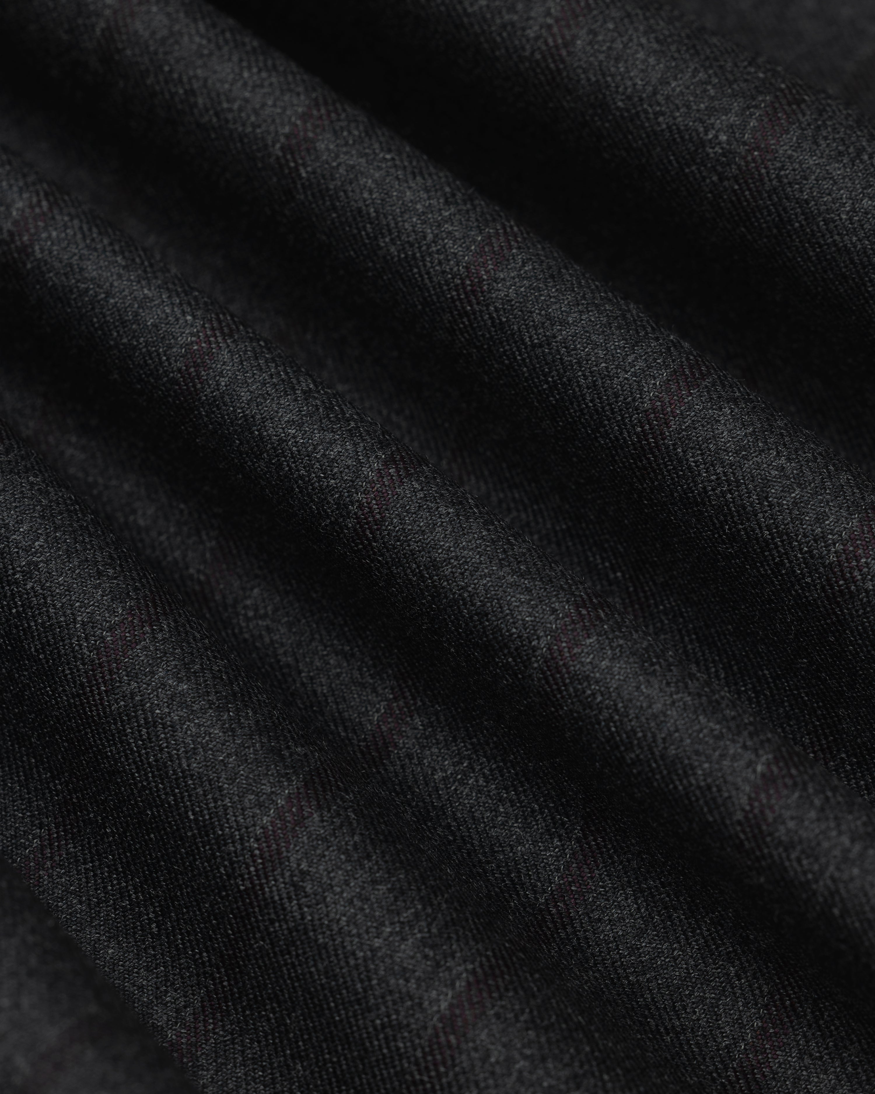 Close-up of a Collarless Striped Blazer in black fabric with faint, dark red pinstripes in soft folds.