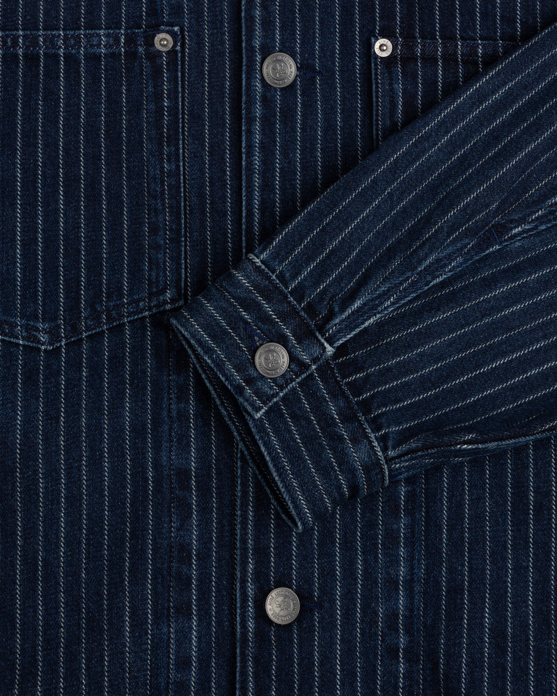 Close-up of the Chalk Stripe Denim Trucker Jacket featuring dark blue pinstripes, metal buttons, and a front pocket.