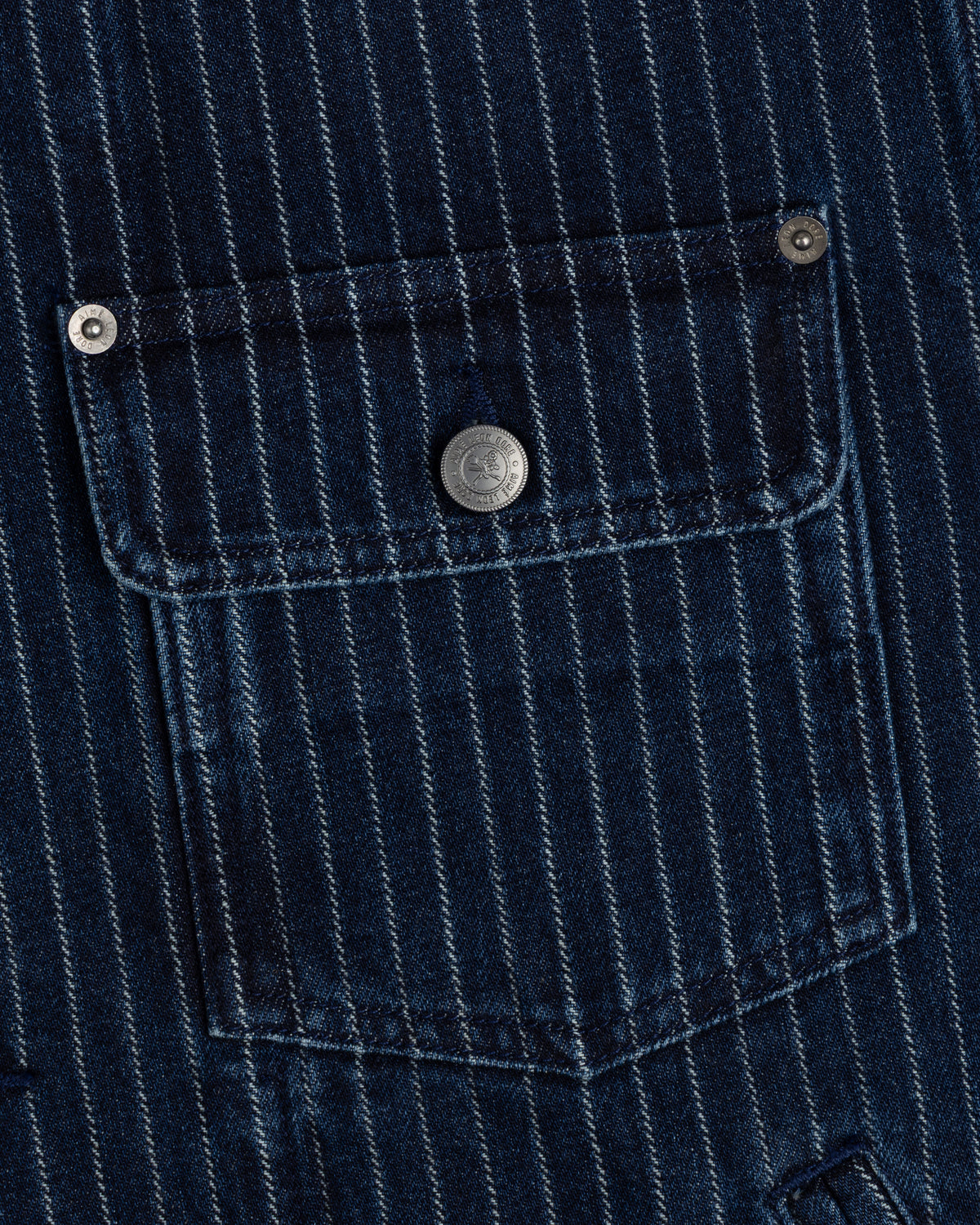 Close-up of Chalk Stripe Denim Trucker Jacket’s blue pinstriped pocket with silver buttons on the flap and corners.