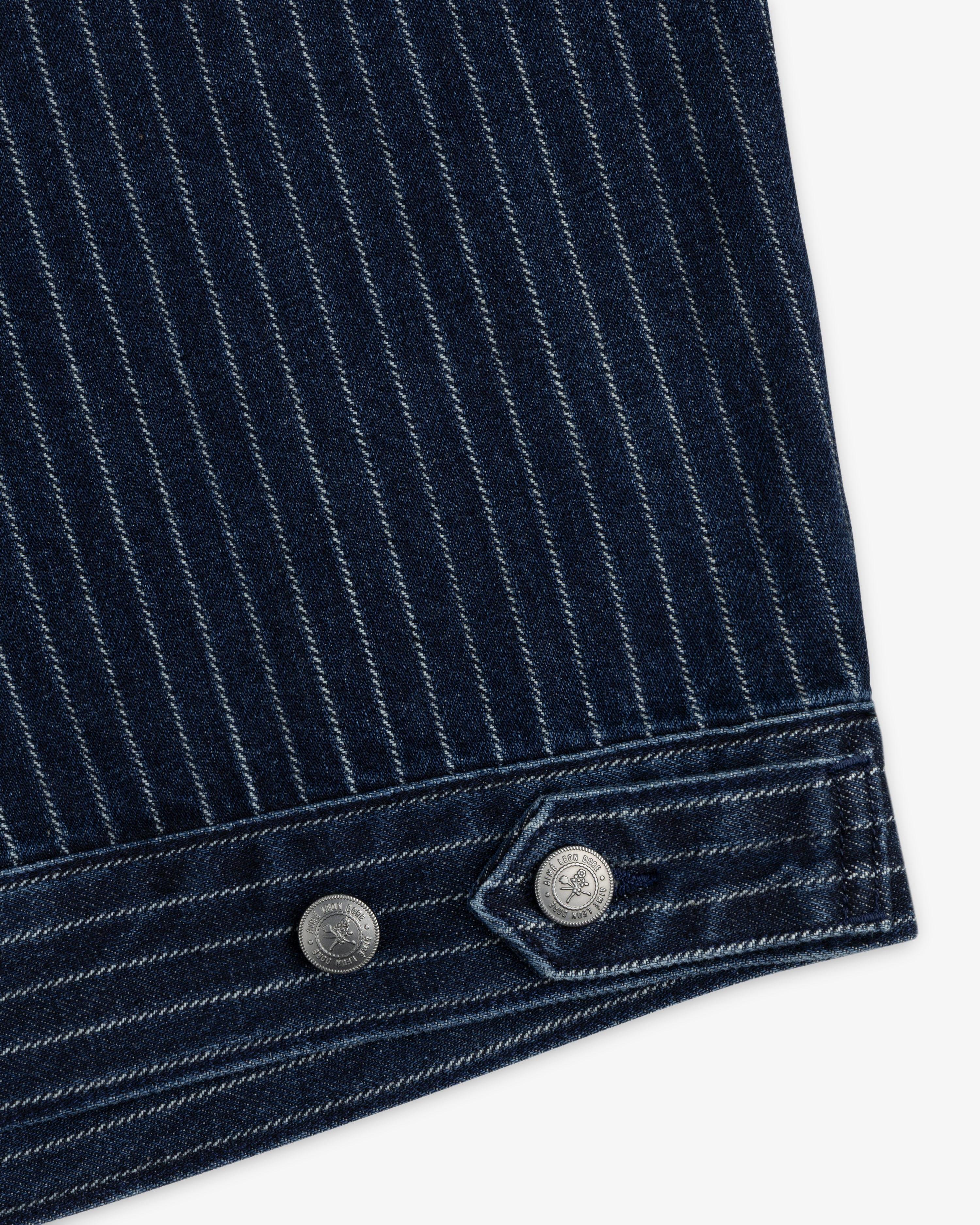 Close-up of Chalk Stripe Denim Trucker Jacket: dark blue denim with white pinstripes, two metal buttons at the hem.