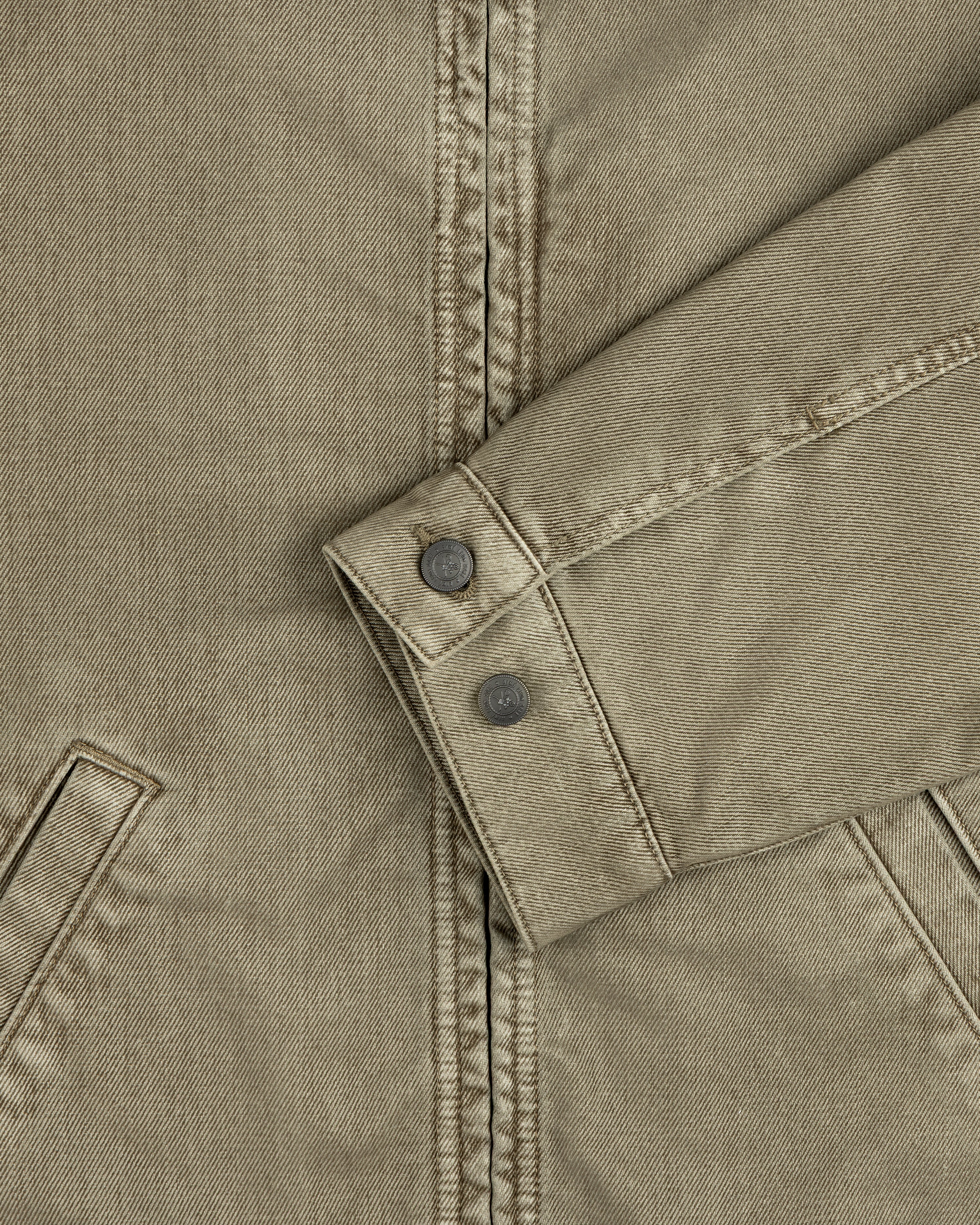 Olive green sleeve of a Flocked Denim Jacket featuring a buttoned cuff.