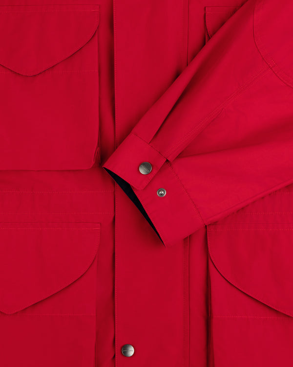 Close-up of the Lightweight Barn Jacket in red, featuring snap buttons, front pockets, and a folded sleeve across the chest.