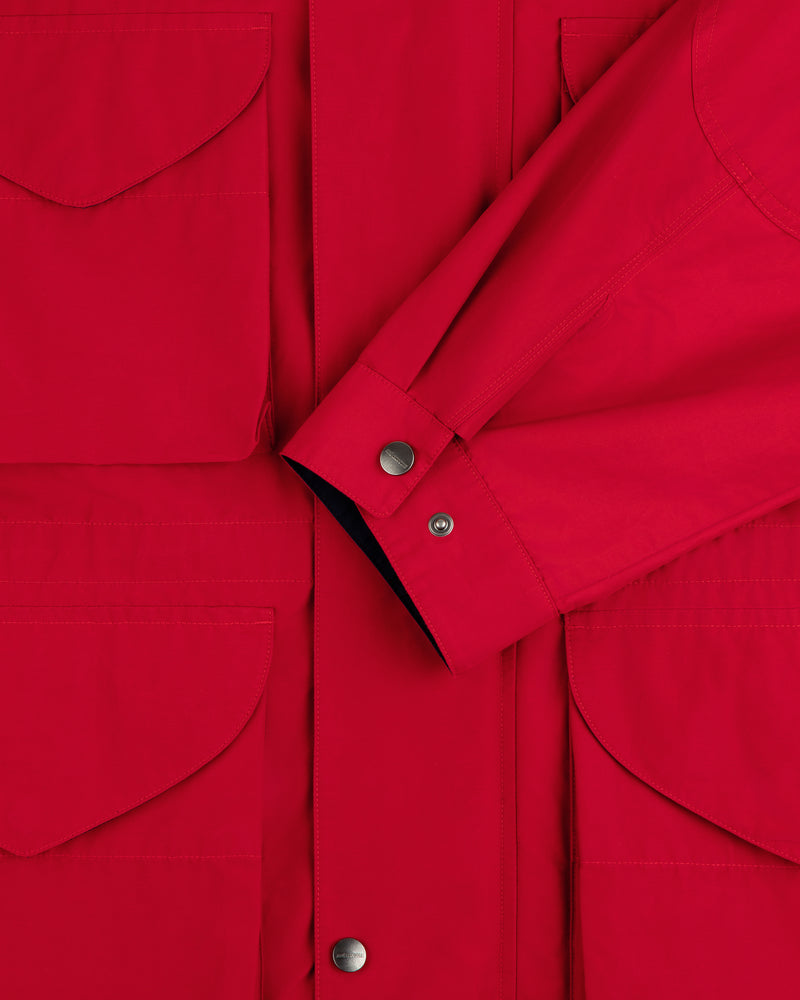 Close-up of the Lightweight Barn Jacket in red, featuring snap buttons, front pockets, and a folded sleeve across the chest.