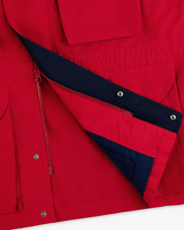 Close-up of a Lightweight Barn Jacket in red, partially unzipped to reveal its dark blue lining and pocket.