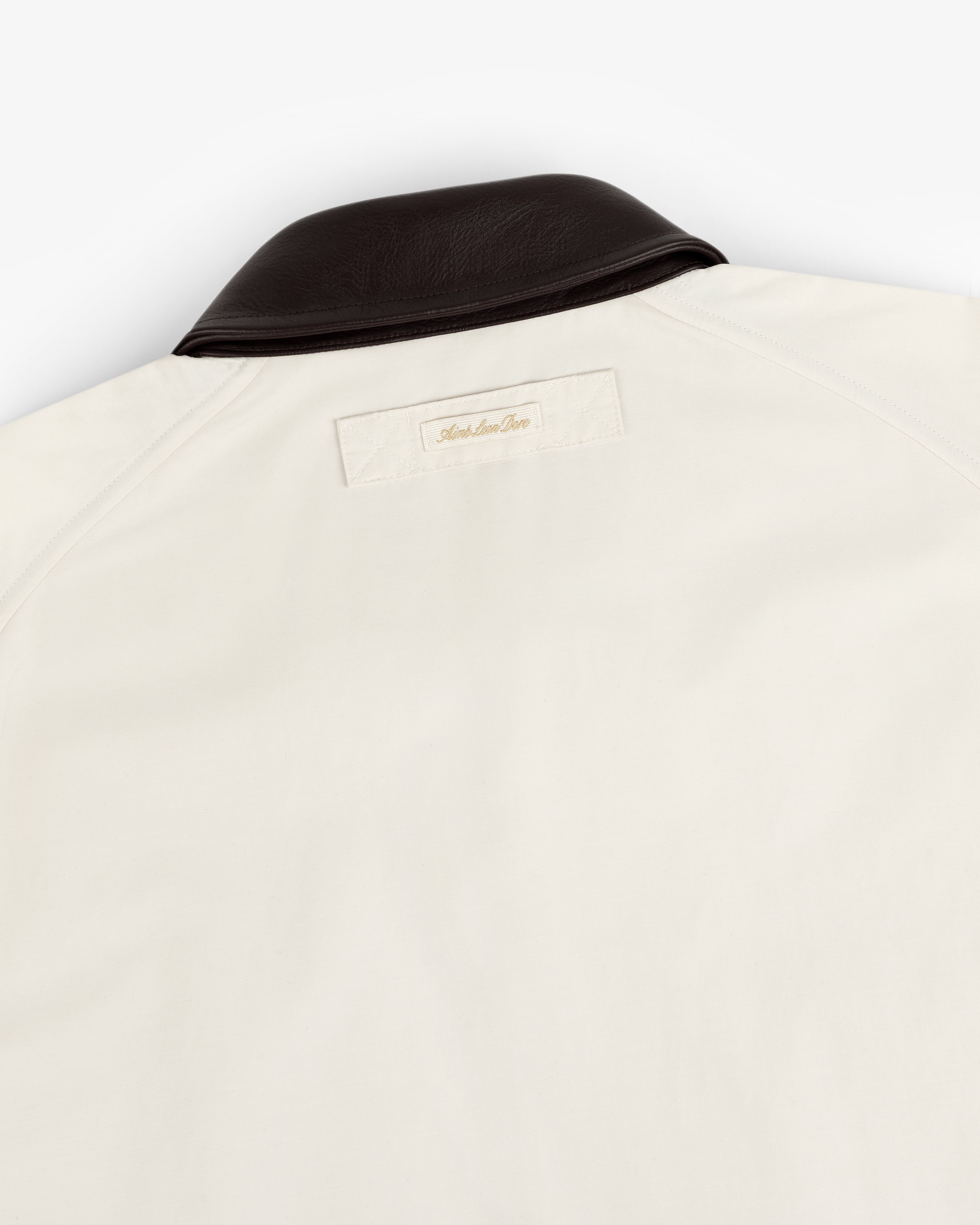 Lightweight Barn Jacket in cream with a dark brown leather collar and a small label stitched below the upper back collar.