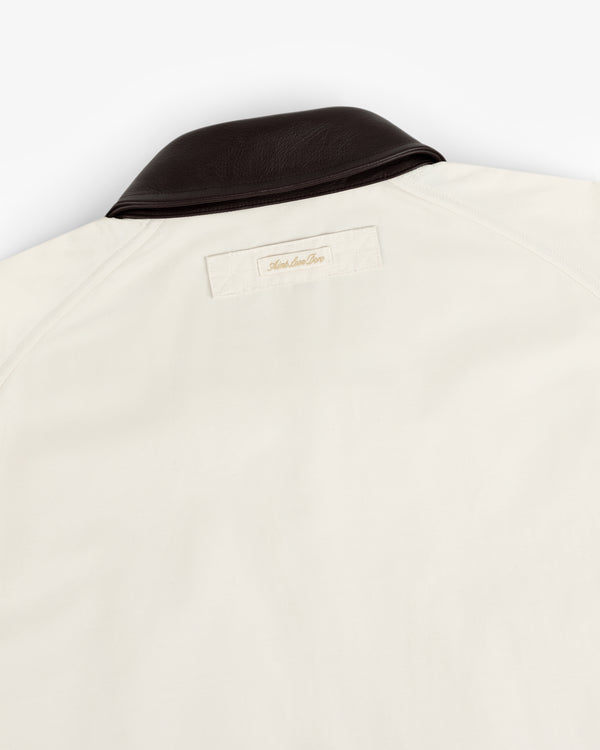 Lightweight Barn Jacket in cream with a dark brown leather collar and a small label stitched below the upper back collar.
