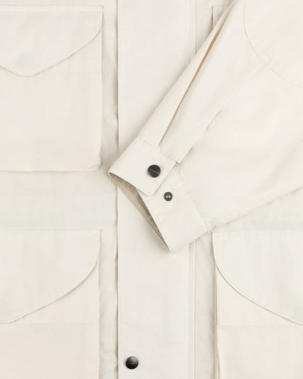 A close-up of the Lightweight Barn Jacket in cream with flap pockets and black snap buttons on front and cuffs.