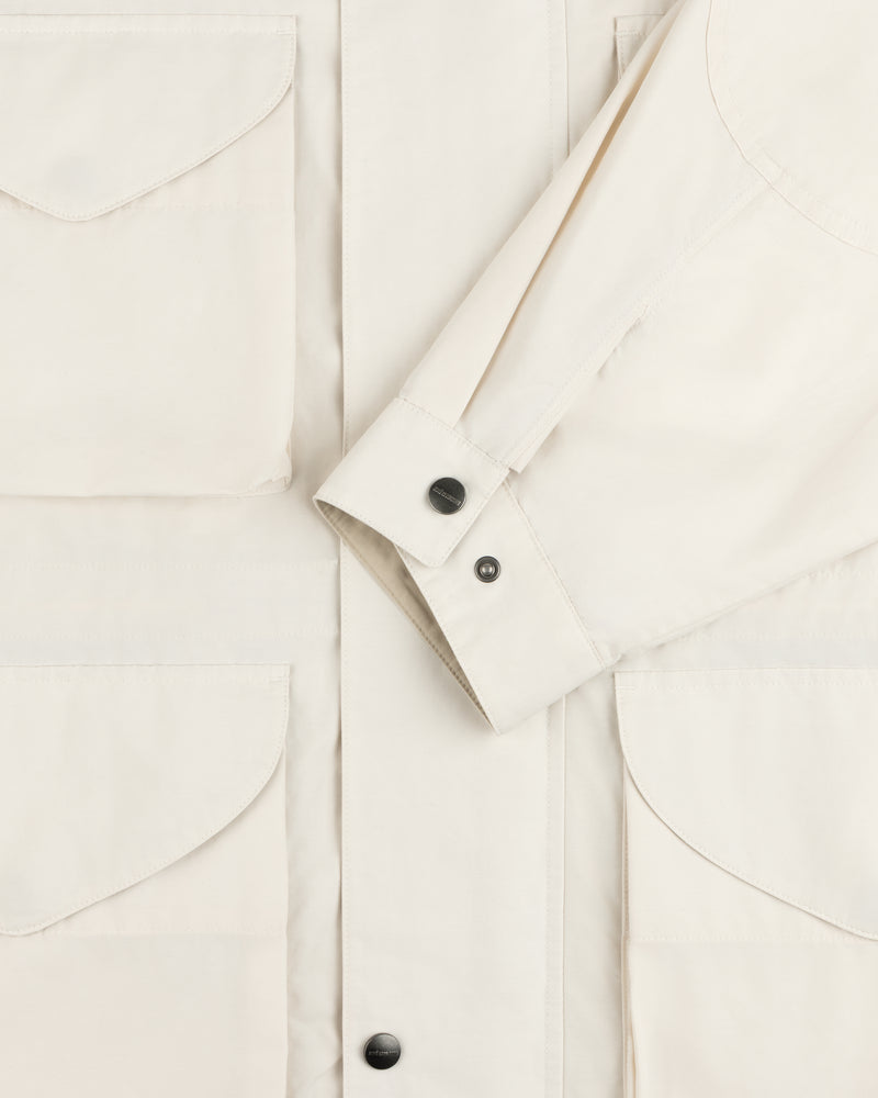 A close-up of the Lightweight Barn Jacket in cream with flap pockets and black snap buttons on front and cuffs.